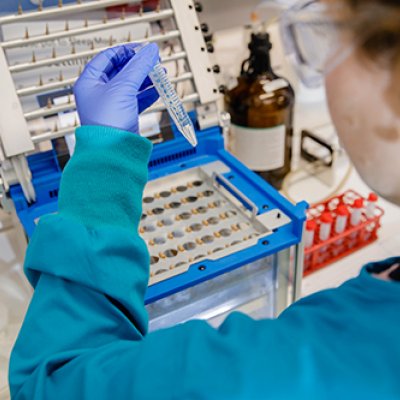 Back of researcher in lab holding up test tube of liquid